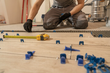 Repair and construction. Laying ceramic tiles using cement on the floor close-up. A man lays slabs...