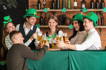 Group of young people with beer celebrating St. Patrick's Day in bar