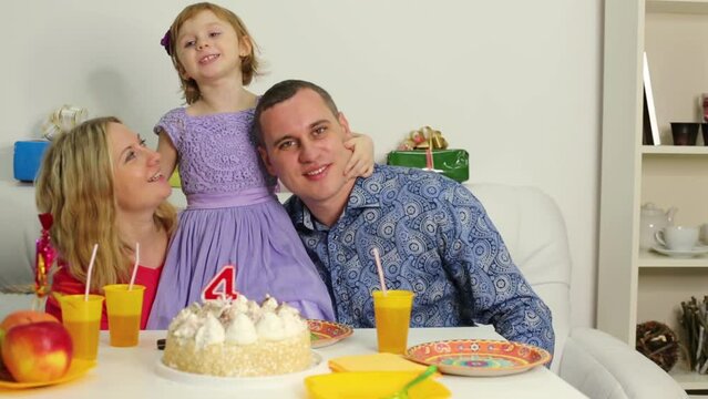 Little girl is kissing and hugging parents at birthday table