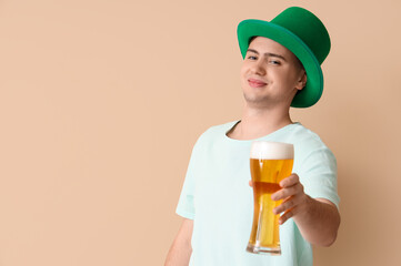 Young man with beer on beige background. St. Patrick's Day celebration