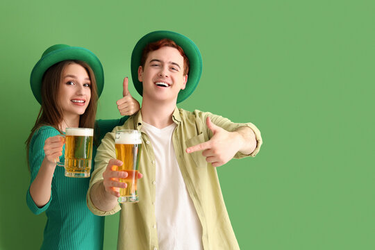 Young couple with beer on green background. St. Patrick's Day celebration
