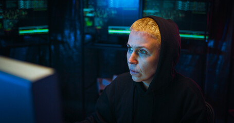 Close up of Caucasian woman cyber police worker sitting in front of computer screen at night and working. Female hacker thinking hard while creating virus or antiviris. Difficult IT work concept.