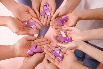 People with lavender awareness ribbons on pink background, closeup. World Cancer Day - obrazy, fototapety, plakaty