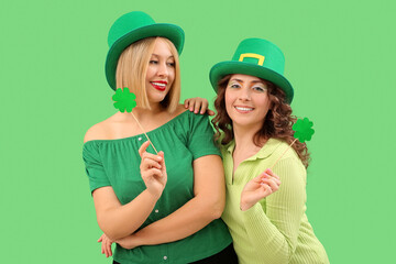 Happy women with paper clovers on green background. St. Patrick's Day