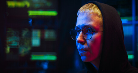 Caucasian cyberpolice woman in glasses and black hood sitting at computer screen as working at...