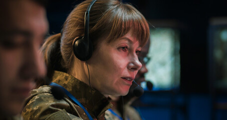 Caucasian military woman in headset sitting at computer and talking via videochat in controlling...
