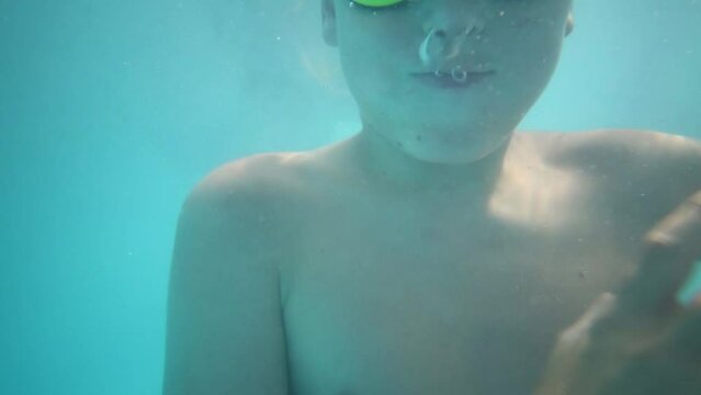 Boy in glasses dives in pool at summer day and face of diving girl