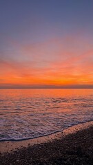Sunset on the sea, the sun goes beyond the horizon, orange sunset and clouds