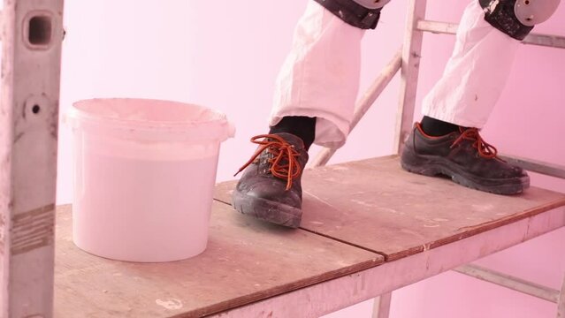Feet of colourer with brush working in new pink room