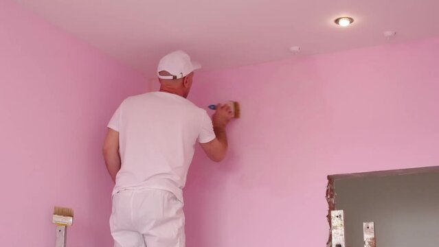 Back of colourer in white clothes and cap working in new room