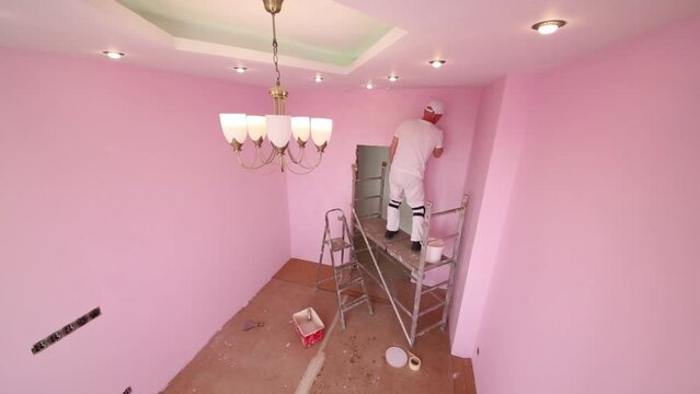 Finisher with brush in hand standing on scaffolding and painting