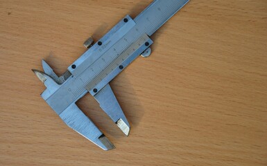 Calipers. Vernier calipers for precise measurements. old working tool on a wooden light background.