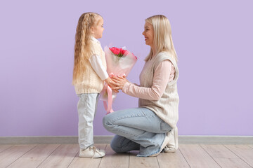 Little girl greeting her mother with tulips near lilac wall. International Women's Day celebration