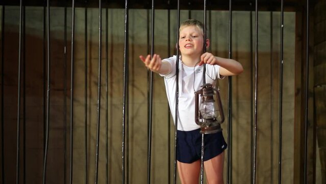 Boy in white t-shirt with kerosene lamp at cell for wild animals.