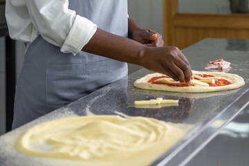 Dark-skinned woman preparing dough for pizza