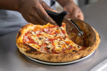Close up picture of females hands cutting pizza