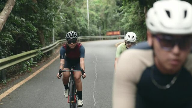 young asian adult cyclists riding bicycle outdoors on rural road