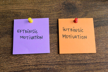 Concept of Extrinsic Motivation or Intrinsic Motivation write on sticky notes isolated on Wooden Table.