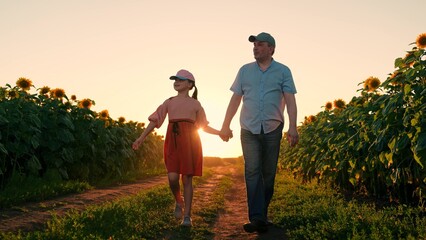 Happy family, father, daughter, child walking through sunflower field, summer. Family business,...