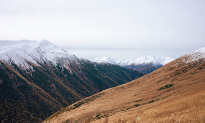 seasonal colors contrast with the pristine snow that caps the distant mountains, a breathtaking blend of fall and winter.