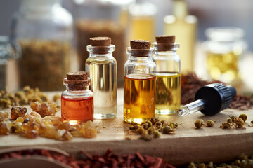 Bottles of aromatherapy essential oils with frankincense resin and dried herbs
