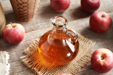 A jug of apple cider vinegar with fresh apples