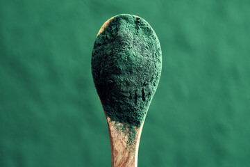 Green spirulina algae powder on a spoon, top view