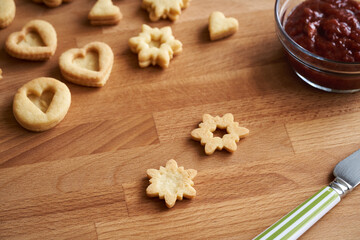 Preparation of traditonal Linzer Christmas cookies - filling with strawberry marmalade