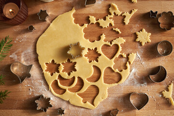 Cutting out star and other shapes from rolled out dough to prepare Linzer Christmas cookies
