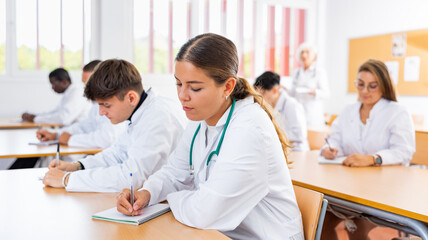 Doctors different age sitting at desk in classroom working during lesson at adult education class