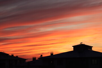 A dramatic sunset with radiant hues of orange and red streaking across the sky, silhouetting the...