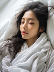 A beautiful Asian woman sleeping soundly under a white blanket