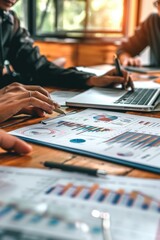 A group of people sitting at a table, all working on their laptops. This image can be used to represent teamwork, collaboration, or a modern office setting