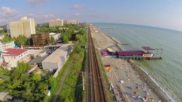 Railway tracks near coastal city and sea beach with people