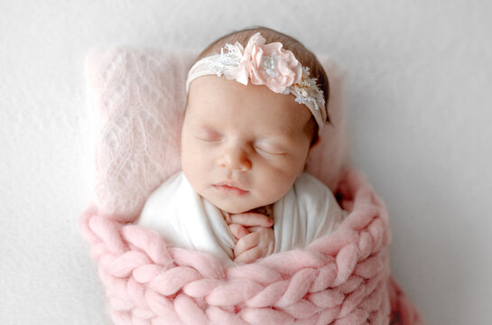 Baby Girl Sleeps Under Blanket With Headband In Newborn Photo Session At Studio
