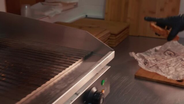 Chef in black gloves making burge. Close-up of a skilled craftsman working at the workplace with burger bun