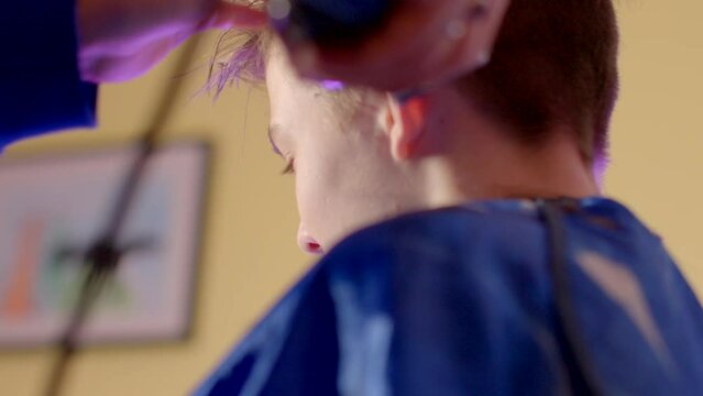 Close-up Clipper Haircut: Crafting Adolescent Self-Image and Style Formation. Transformative process as clipper shapes and defines boys hair, formation of a unique adolescent self-image and style.