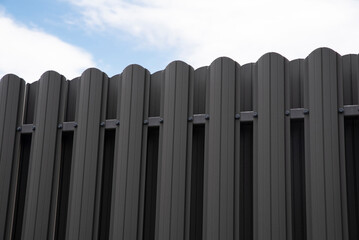 Modern metal picket fence on sky background