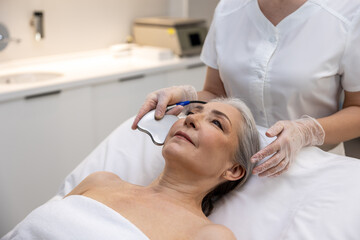 Mature woman having beauty procedure at cosmetological clinic