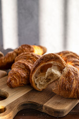Close-up of croissants on wooden board, illuminated by soft natural light.