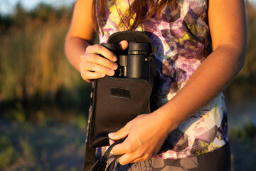 Unrecognizable brunette woman in sportswear taking out or keeping binoculars in her case in a...