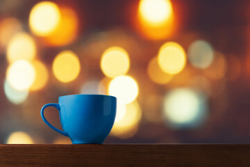 Blue Ceramic Cup on Wooden Table with Bokeh Background Lights