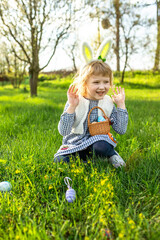 Fototapeta premium little girl hunts for an egg in a spring garden on Easter day. Traditional outdoor Easter celebration.