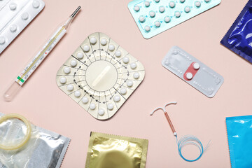 Fototapeta na wymiar Contraceptive pills, condoms, intrauterine device and thermometer on beige background, flat lay. Different birth control methods
