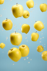 Bright yellow apples captured in mid-air with sparkling water droplets on a light blue background, depicting freshness and levity.
