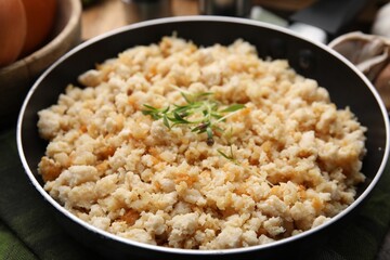 Fried ground meat in frying pan and microgreens on table, closeup