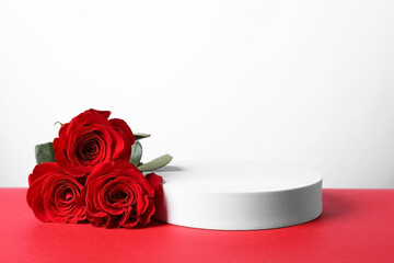 Stylish presentation for product. Round podium and beautiful roses on red table against white background, space for text