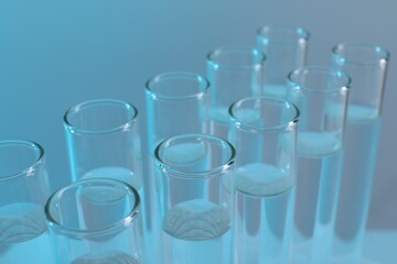 Laboratory analysis. Many glass test tubes on light blue background, closeup