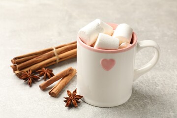 Fototapeta na wymiar Tasty hot chocolate with marshmallows and spices on light grey table, closeup