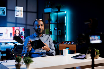 African american man filming tech tutorial on how to do maintenance on broken tablet, presenting...